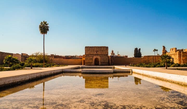El Badi Palace in Marrakech under a clear blue sky with a reflecting pool in the foreground.