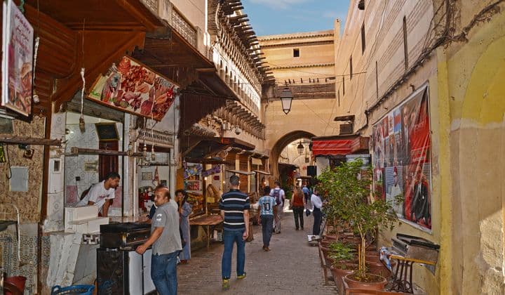 Vibrant street scene in the Medina of Fès, Morocco, with locals and market stalls.