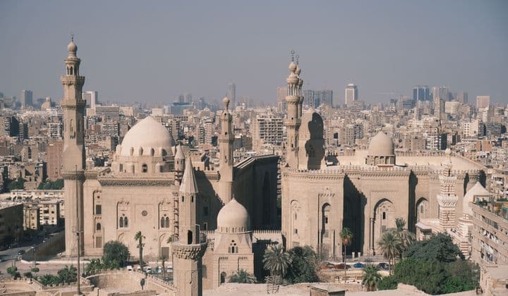 Scenic aerial view of Cairo with the iconic Mosque-Madrassa of Sultan Hassan and city skyline.