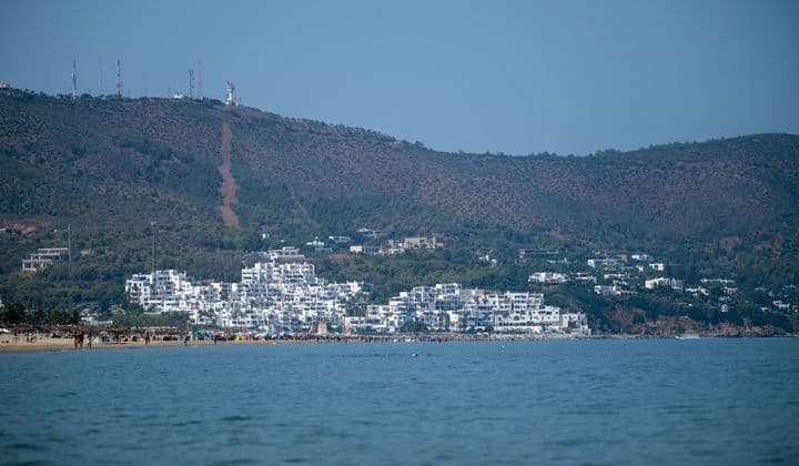 Breathtaking coastal view with white buildings and lush hills in Tétouan, Morocco.