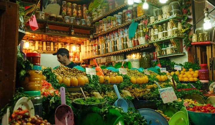 Colorful array of spices and produce in a bustling market stall in Fes, Morocco.