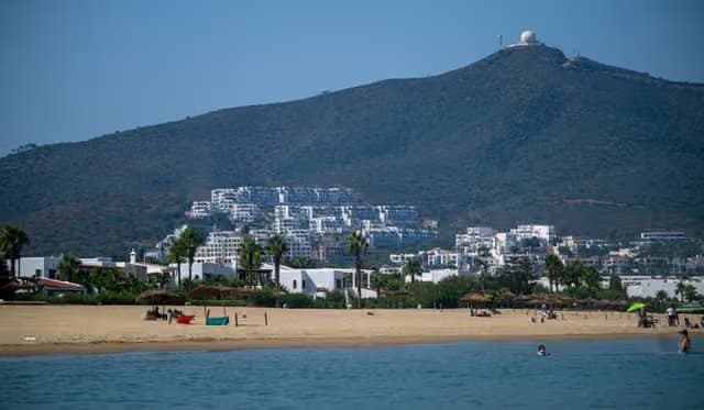 A picturesque view of the beach and hillside buildings in Tétouan, Morocco under a clear blue sky.